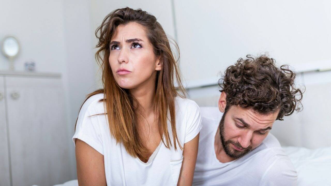 A man looks down sadly while a woman with a worried expression looks up.