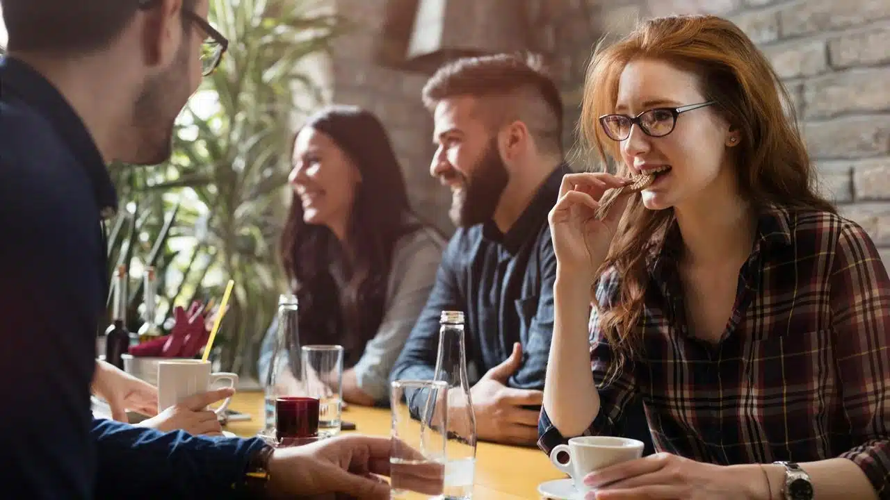 A group of friends chatting and enjoying coffee together at a café table.