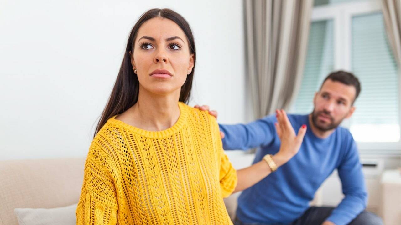 A man is touching the shoulder of a woman; the woman is gesturing to refuse to talk to him.