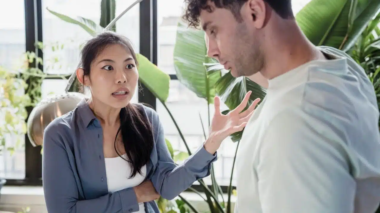 A woman is gesturing with a frustrated expression while talking to a man.